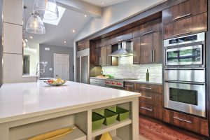 The contemporary theme of this open kitchen intensifies with the use of contrasting dark cabinetry against a white island in a $80,000 to $120,000 remodel by Realty Restoration of Austin Tex.